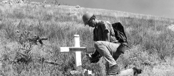 Recreation Guard Fred Patten in the Mann Gulch next to smokejumper Leonard J. Piper's memorial