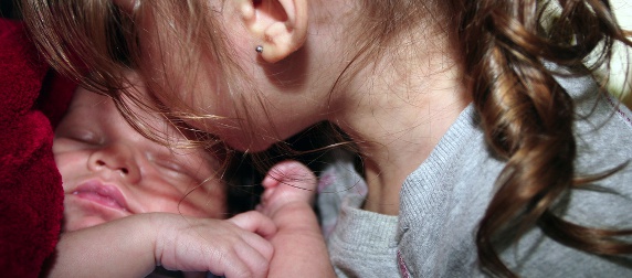 sister kissing baby