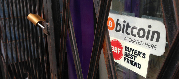 door sign reading 'bitcoin accepted here' behind a security gate