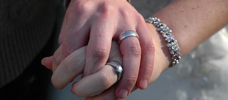 Two hands clasped displaying their wedding rings