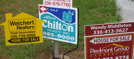 a cluster of real estate for sale signs