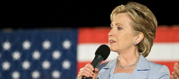 Hillary Clinton in 2008, speaking with a microphone in front of an American flag