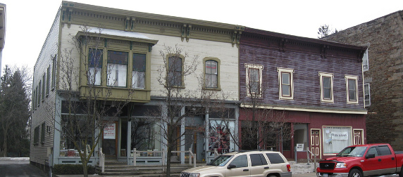 empty storefronts along a street with parked cars