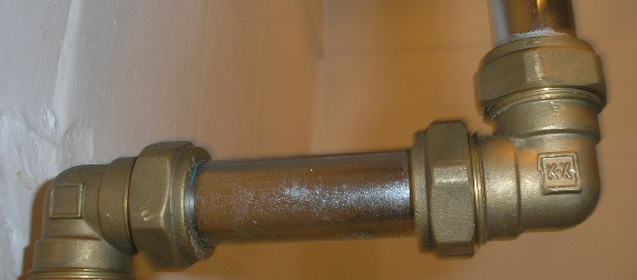 metal plumbing pipes against a white brick wall