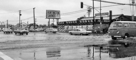 flooding in a parking lot outside a Food Ranch in California circa 1969, with cars and a VW bus