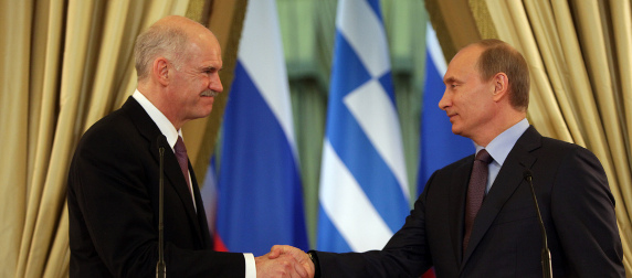 George Papandreou and Vladimir Putin shake hands in front of Greek and Russian flags