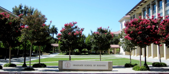 outdoor sign for the Stanford Graduate School of Business surrounded by flowering trees in bloom