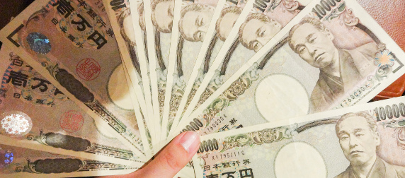 10,000 yen notes, fanned behind a thumb