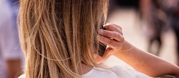 individual with long, blond hair tlaking on a cellphone, seen from behind