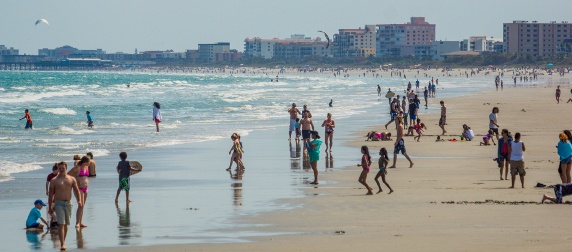 people on a beach near Cape Canaveral, Florida, with developments on the horizon