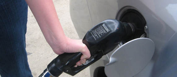 hand holding a gas pump filling the tank of a silver car