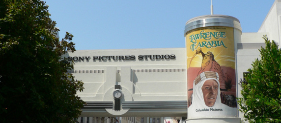 Sony Pictures Studios' entrance, with a column advertising Laurence of Arabia and trees in the foreground