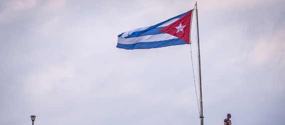 Cuban flag, reversed by the wind, with a man and lamppost below