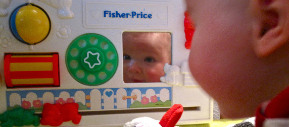 infant's face reflected in mirror of Fischer-Price busy box