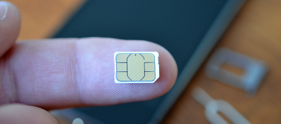 extra-small SIM card on the pad of a person's finger