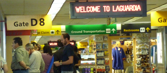 a sign reading Welcome To LaGuarida above travellers waiting in line
