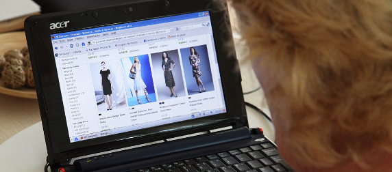 person with blond hair looking at dresses in an online store on a laptop computer