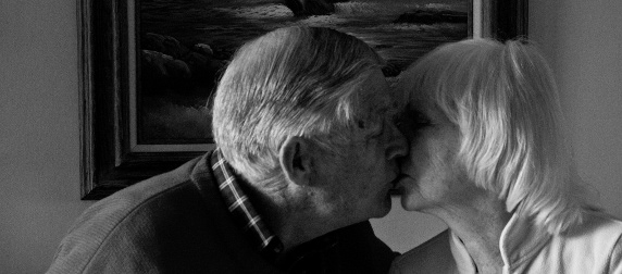 black and white image of older couple in profile, kissing