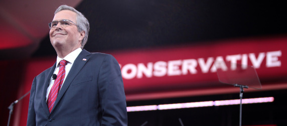 Jeb Bush on stage with teleprompter, backdrop reading CONSERVATIVE in the background