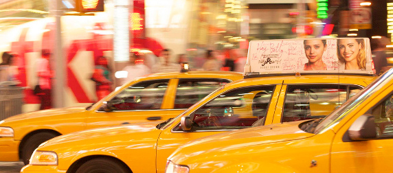 three yellow taxis against a blurry urban night scene