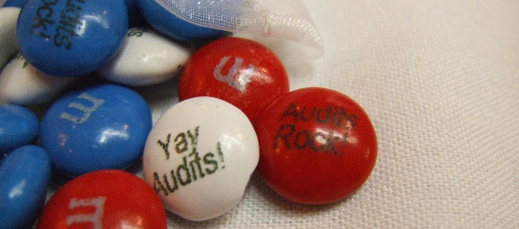 red, white and blue M&M's with custom messages reading Yay Audits! and Audits Rock! against a white tablecloth