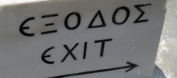 black and white image of a stone sign that reads Exit in Greek and English with an arrow pointing right