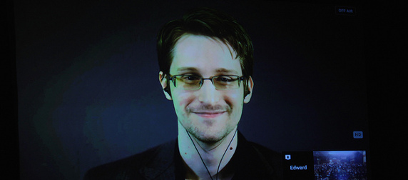 Edward Snowden, wearing earbuds, appearing on a projection screen