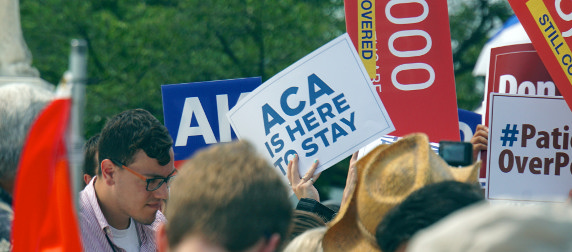 protestors with signs, one reading ACA Is Here To Stay