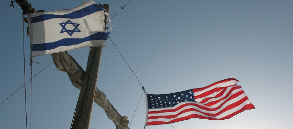 Israeli and American flags flying on either side of a ship's mast, viewed from below