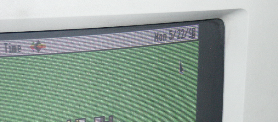 detail of a CRT Macintosh monitor with the date 5/22/<? and a cursor on a green background