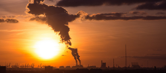 factory smokestack seen against a setting sun