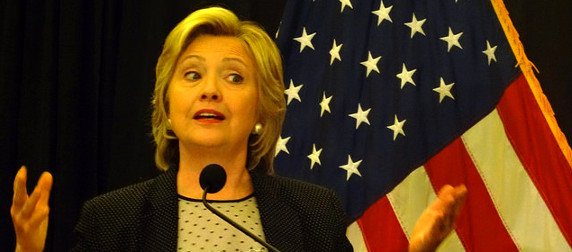 Hillary Clinton, at a podium, in front of an American flag