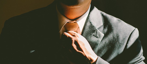 close-up of a person in a suit adjusting a necktie