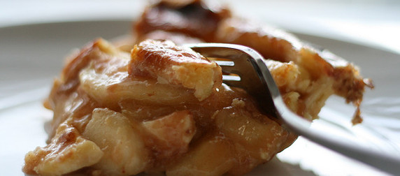 piece of apple pie on a white plate, cut with a fork