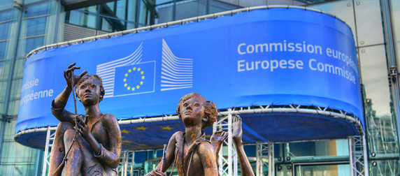 statue of children outside the Berlaymont building in Brussles, with a European Commission banner in the background