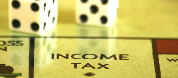 dice on a Monopoly board above the Income Tax space