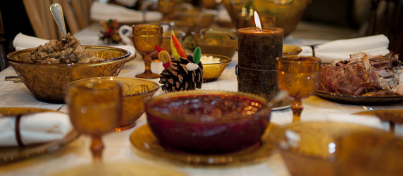 Thanksgiving table with turkey, stuffing, cranberry sauce, place settings, candles and turkey pine cone decorations