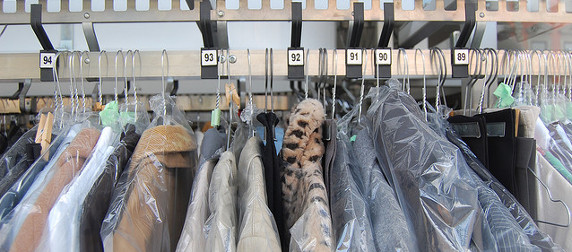 detail of dry-cleaned clothes in bags hanging with tags