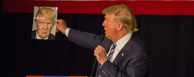 Donald Trump holding up a copy of Time magazine featuring his photo and the title Deal With It