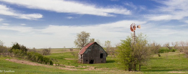 an abandoned barn and weathervane against a rural landscape in summer