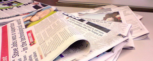 fanned-out pile of newspapers on a white desk