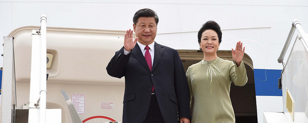 Xi Jinping and Peng Liyuan waving from the door of an airplane