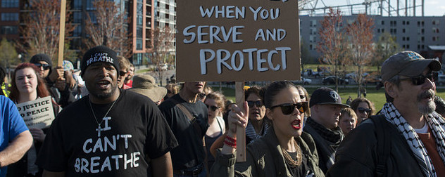 protesters with signs reading No Justice, No Peace; I Can't Breathe; and a partial sign reading When You Serve and Protect