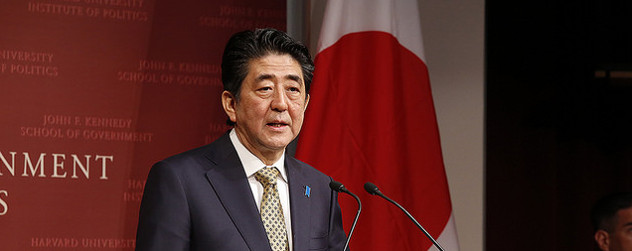 Shinzo Abe speaking in front of a Japanese flag at the John F. Kennedy School of Government