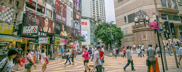 shoppers walk among storefronts and billboards in Hong Kong