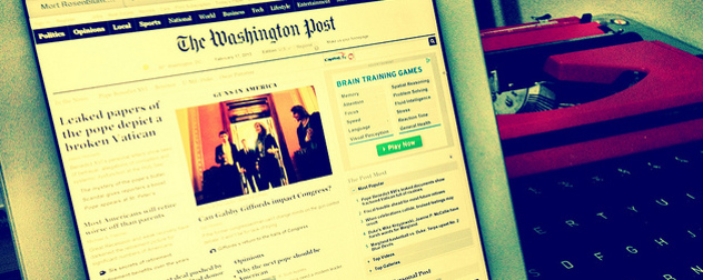 The Washington Post homepage displayed on an iPad, a typewriter in the background