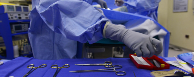 gloved hand reaching for something on a surgical insturment table