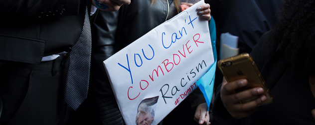 protest sign with a picture of Donald Trump and the slogan 'You can't combover racism'