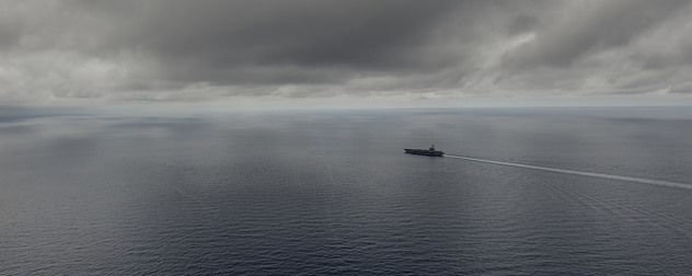 distant view of the USS Ronald Reagan on the South China Sea under a cloudy sky