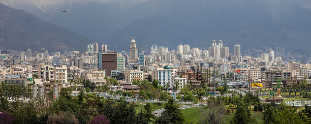 downtown Tehran, viewed against the mountains with an airplane in the distance